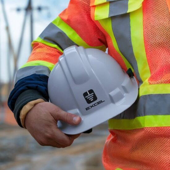 Excel Electric Contractor holding a gray hard hat and wearing an orange safety vest